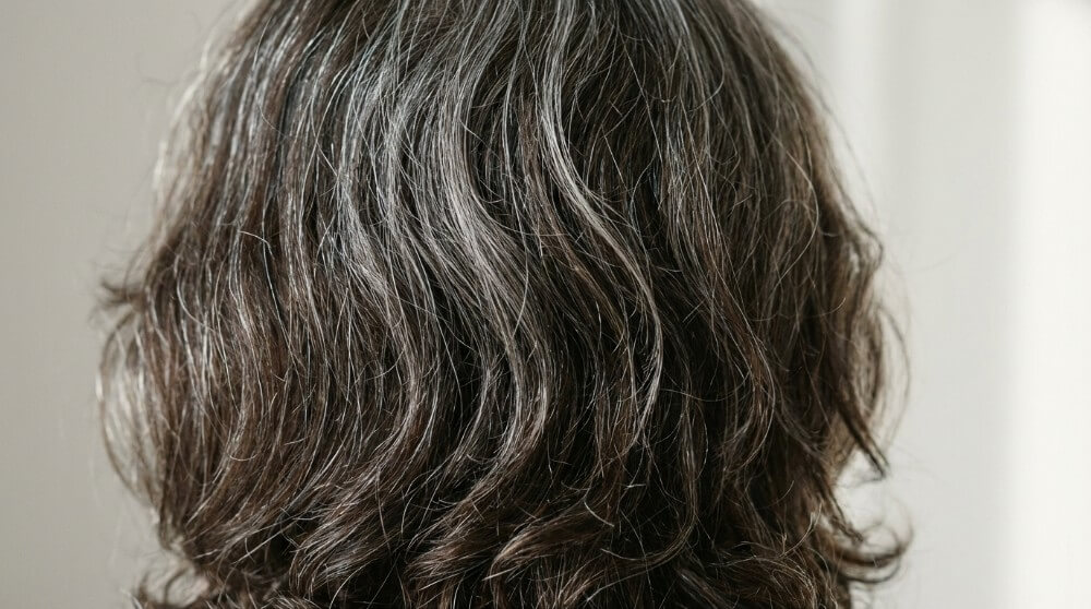 Naturalne siwienie włosów, widoczne pojedyncze siwe pasma wśród ciemniejszych włosów