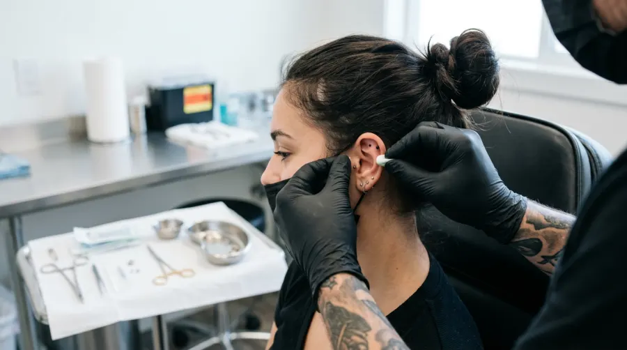 Piercer w rękawiczkach przygotowujący ucho do bezpiecznego zabiegu