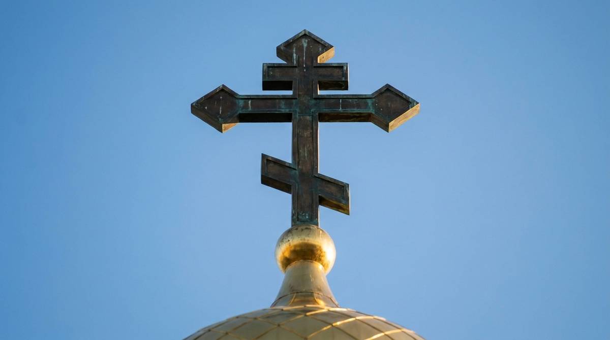 Krzyż prawosławny z trzema belkami na złotej kopule cerkwi na tle błękitnego nieba