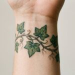 Bluszcz o wiecznie zielonych listkach wytatuowany na nadgarstku, symbol trwałości i przywiązania.