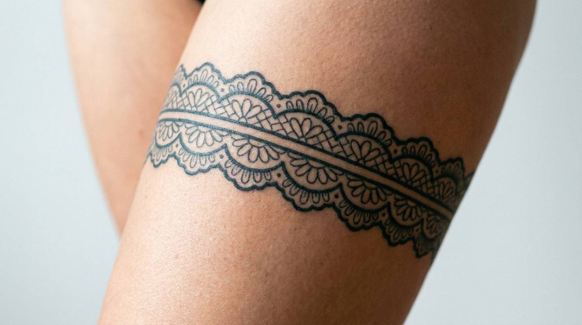 Tatuaż podwiązki w koronkowym wzorze pin-up na udzie, zbliżenie na skórę